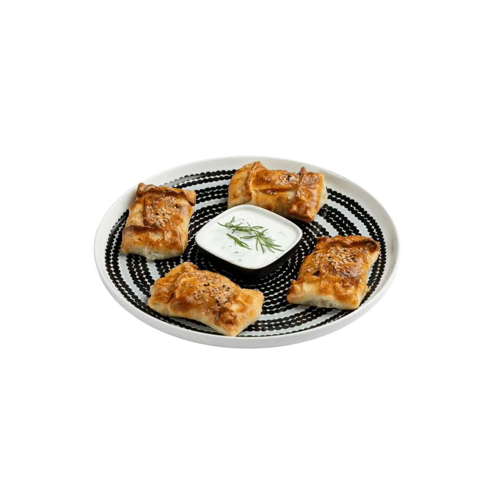 Baked Uyghur samsa pastries with sesame seeds and yogurt dip on a patterned plate